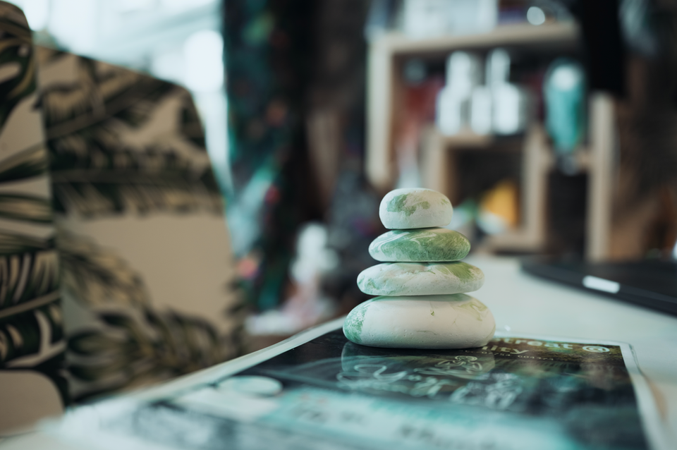 Stacked green stones sitting on a magazine, Serenity Yoga for meditation.