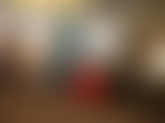 Girl in red dress holding a christmas present in front of a christmas tree 