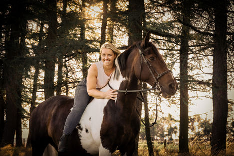 Smiling woman horseback riding in woods