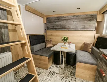 Modern compact living space with dining table, benches, and loft ladder.