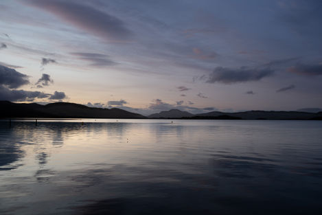 Serene sunset over calm lake, mountains in distance