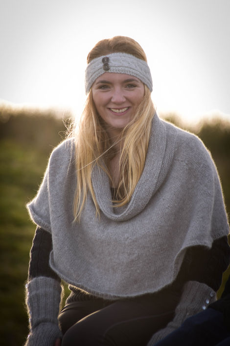 Smiling woman wearing a gray poncho and headband