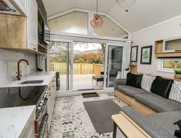 Contemporary open-plan kitchen and lounge leading to scenic autumn outdoor deck.