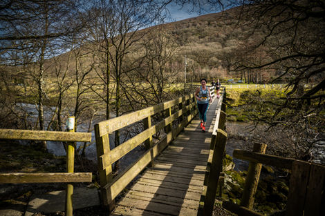 Runner crossing wooden bridge, scenic trail