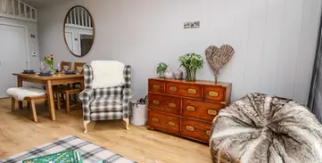 Cozy living dining area with plaid armchair, wooden table, and bean bag.