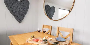 Wooden dining table for two, charcuterie, wine, heart decoration, mirror.