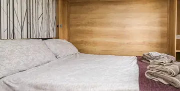 Cozy bedroom with a comfortable bed, light wood, and patterned wall.