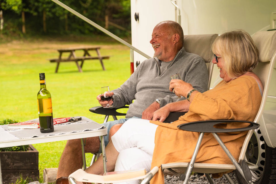 Couple sitting enjoying a glass of wine outside of their motorhome