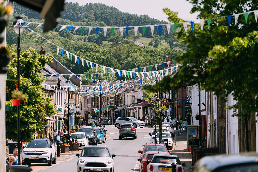 sunny high street with bunting decorating the street, people and cars imply its busyness.