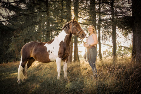 Woman and piebald horse in field