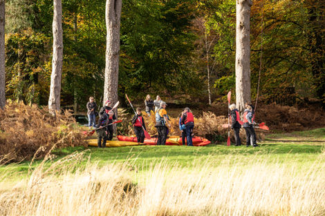 Group kayaking near autumn trees