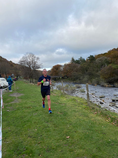 Runner on grass track Rhayader Running Club, near river. EV10 RACE during event.