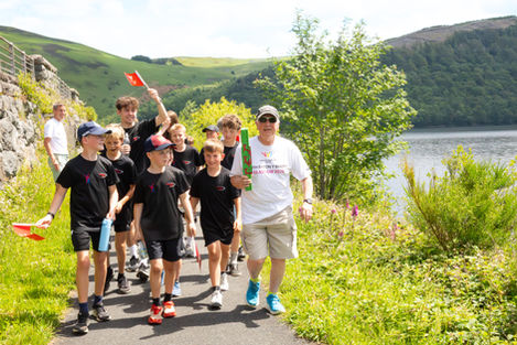 Group walking outdoors near a lake and hills.