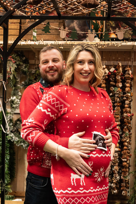 couple in matching Christmas sweaters, announcing pregnancy