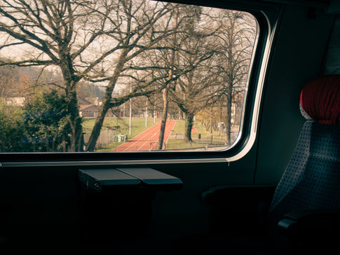 Looking out of a train window onto a sports track and trees