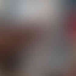 A hand holds two empty baby bottles with breast pump parts attached to the top instead of nipples