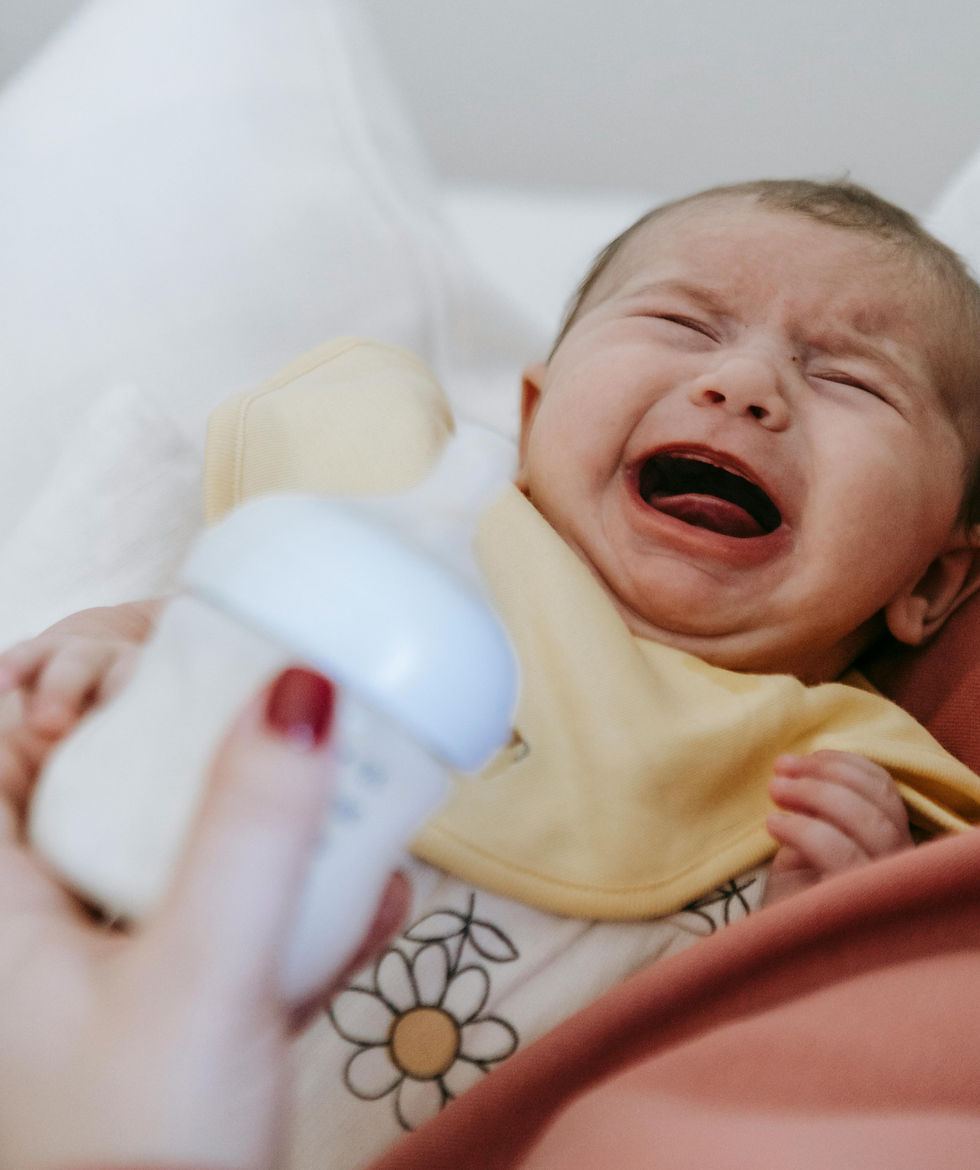 a person is holding a crying baby and a bottle of milk