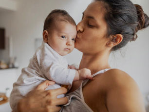a woman is holding a young baby and kissing its face