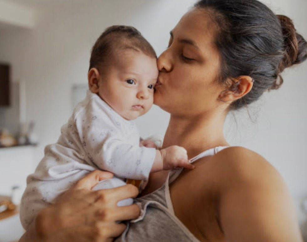 a woman is holding a young baby and kissing its face