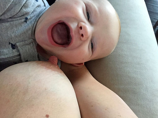 a baby at breast smiles at his mom