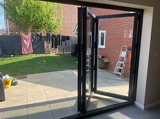 Open glass doors leading to a sunny patio and garden
