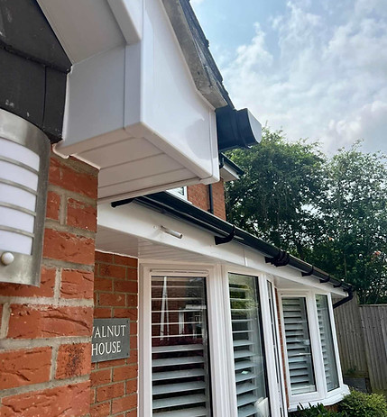 Exterior of a brick house with white window shutters and gutter system