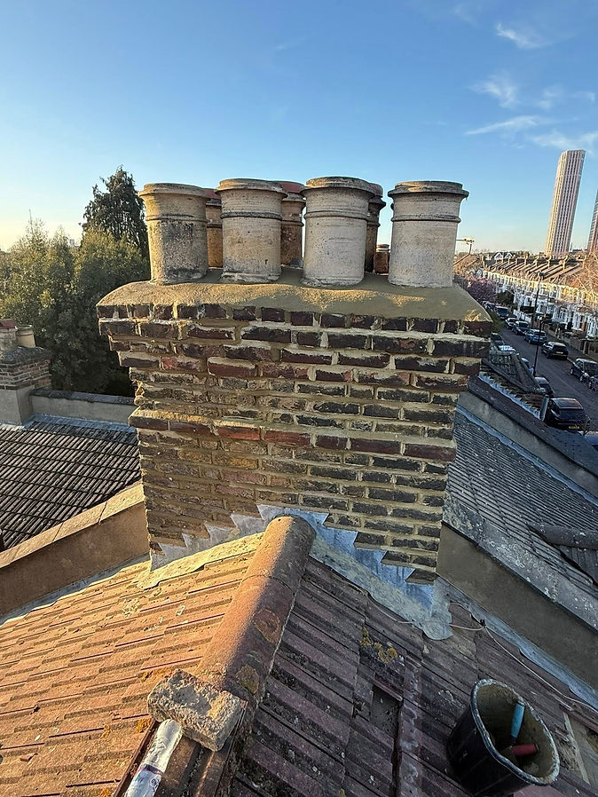 A brick chimney topped with a matching brick chimney cap against a clear blue sky