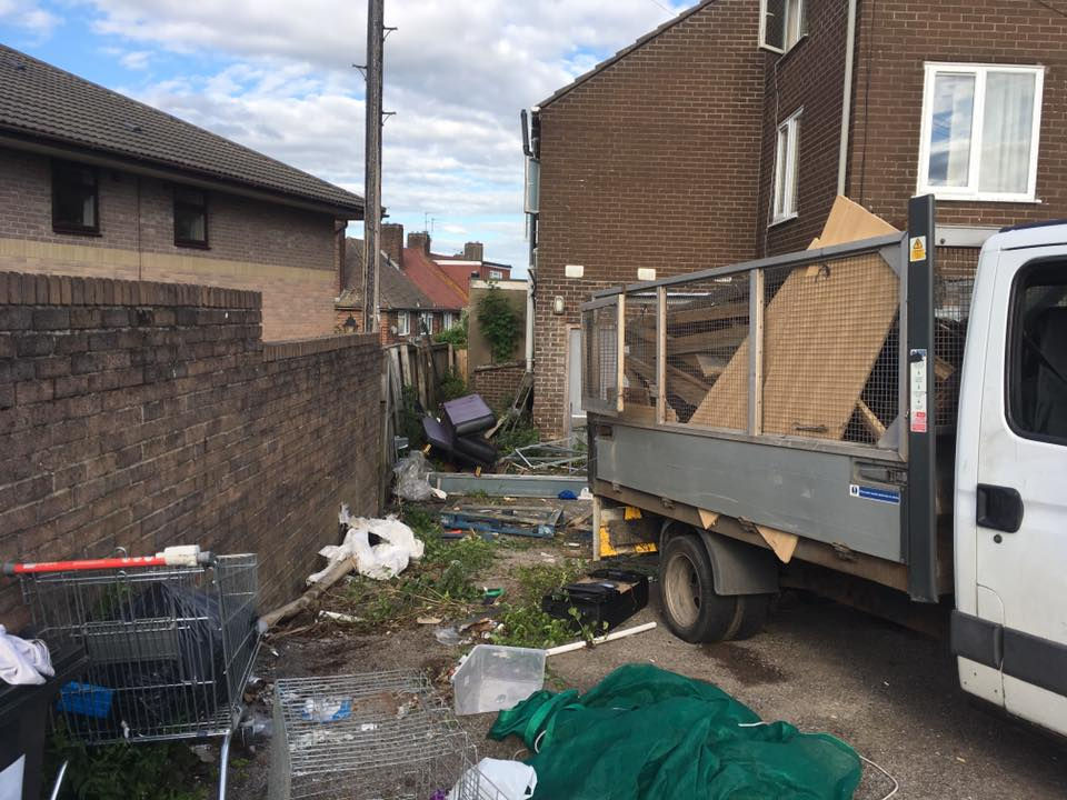 A cluttered alley beside brick buildings with scattered debris