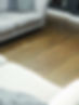 Medium-to-dark rustic wood plank flooring situated beneath a light grey upholstered sofa