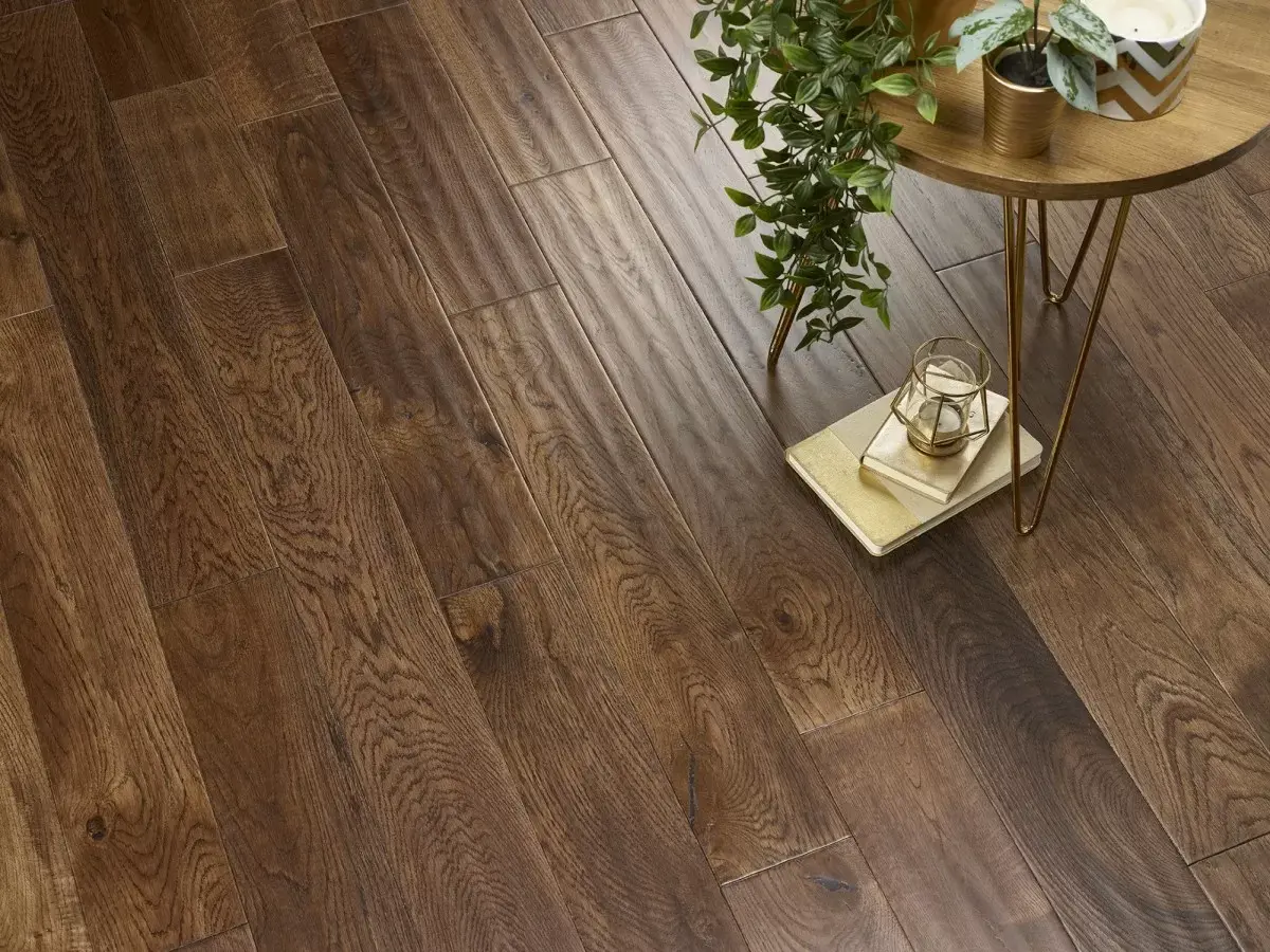 Warm brown wood flooring with visible grain patterns, a small round table with thin gold legs