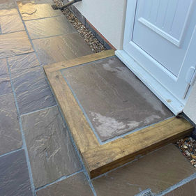 Stone patio with step, white door, rectangular earthy-toned tiles