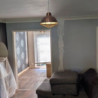 A room under renovation with exposed wall patches and covered furniture