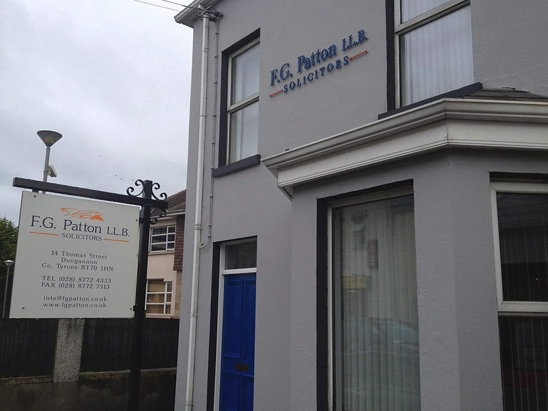 Grey building with blue door, sign reads F.G. Patton