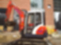 Small excavator with a muddy bucket parked at a construction site
