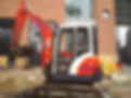 Small excavator with a muddy bucket parked at a construction site