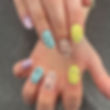 Close up of a creative pastel manicure featuring unique black speckled nail art designs on long nails