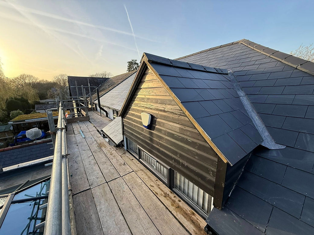A building roof featuring a combination of black slate and metal roofing materials