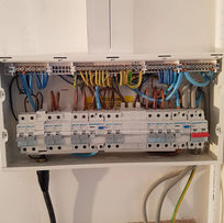 Open white electrical panel with neatly arranged wires and circuit breakers in various colors