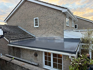 Flat roof extension with smooth, dark surface attached to a brick house