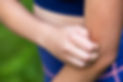 A woman grimaces while holding her arm, indicating she is experiencing pain