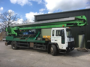 A green and white truck with a long crane arm labeled "G.A Butler & Sons Ltd" is parked