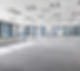 Bright, empty office space with gray carpet, large windows showing a cityscape