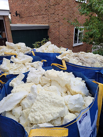 Large blue bags filled with white foam chunks in front of a brick building
