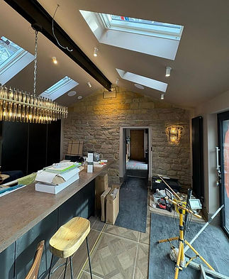 Modern kitchen with a high ceiling, skylights, and a stone accent wall