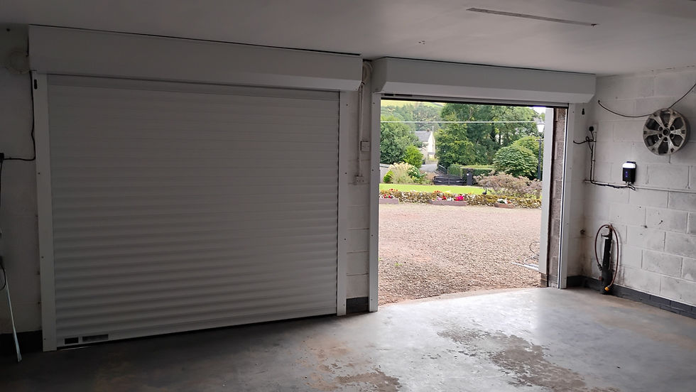 Open garage with a concrete floor and one closed white roll-up door on the left
