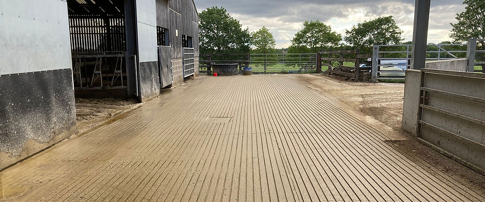 Wooden barn exterior with a textured concrete pathway, bordered by a wooden fence