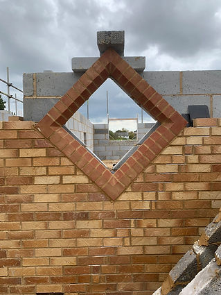 Brick wall with a diamond-shaped window, bordered by red bricks