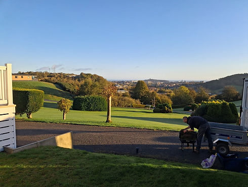 Landscaper using equipment to maintain a manicured, rolling lawn overlooking scenic countryside hills