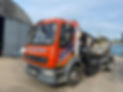 A red and orange GJK Contracts truck is parked in a yard by a large, curved metal building