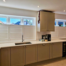 Modern kitchen interior showing white wooden shutters on windows above the counter